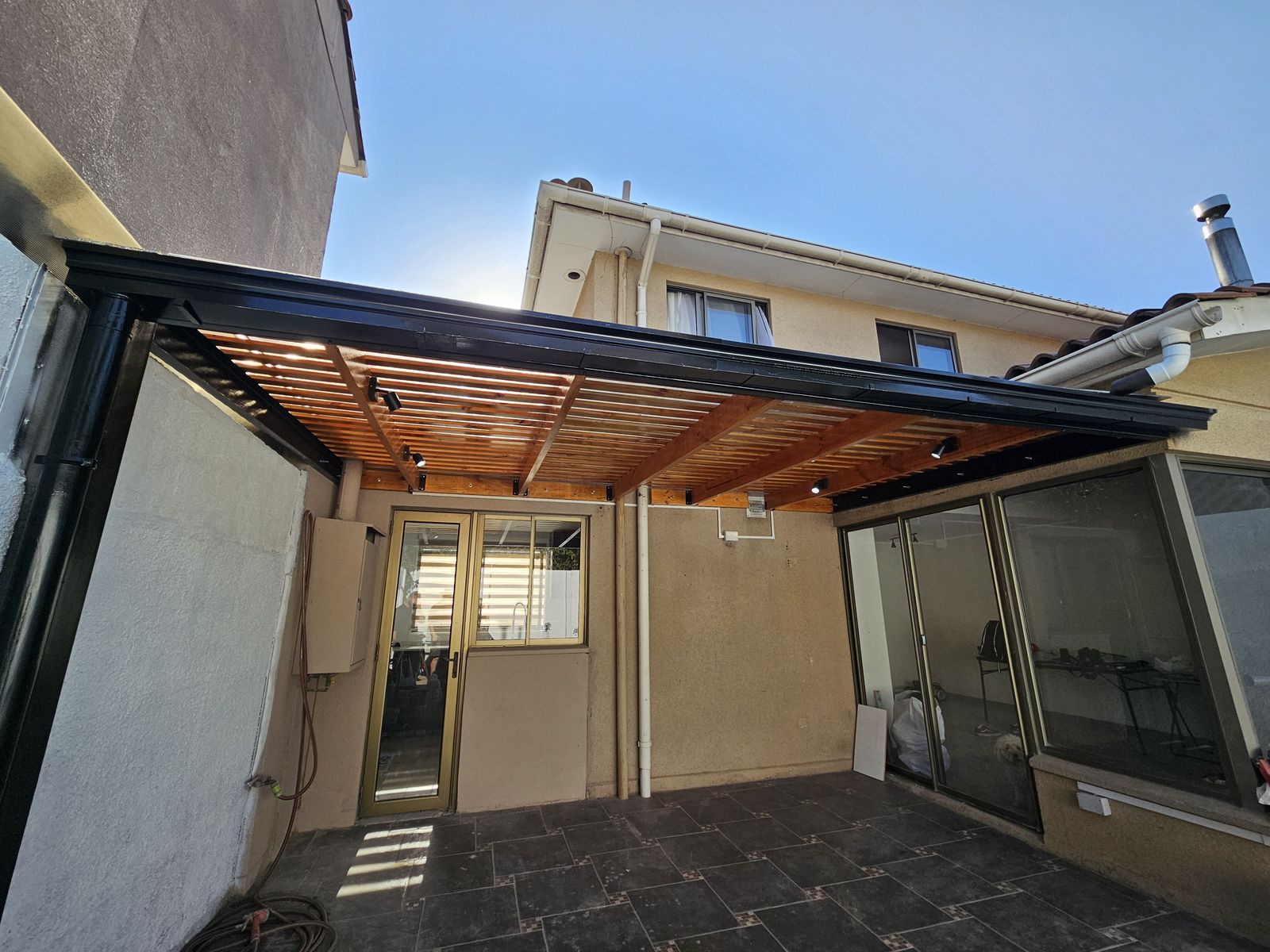 Pérgola metálica con techo de madera e iluminación, fabricada por Galvez y Partners